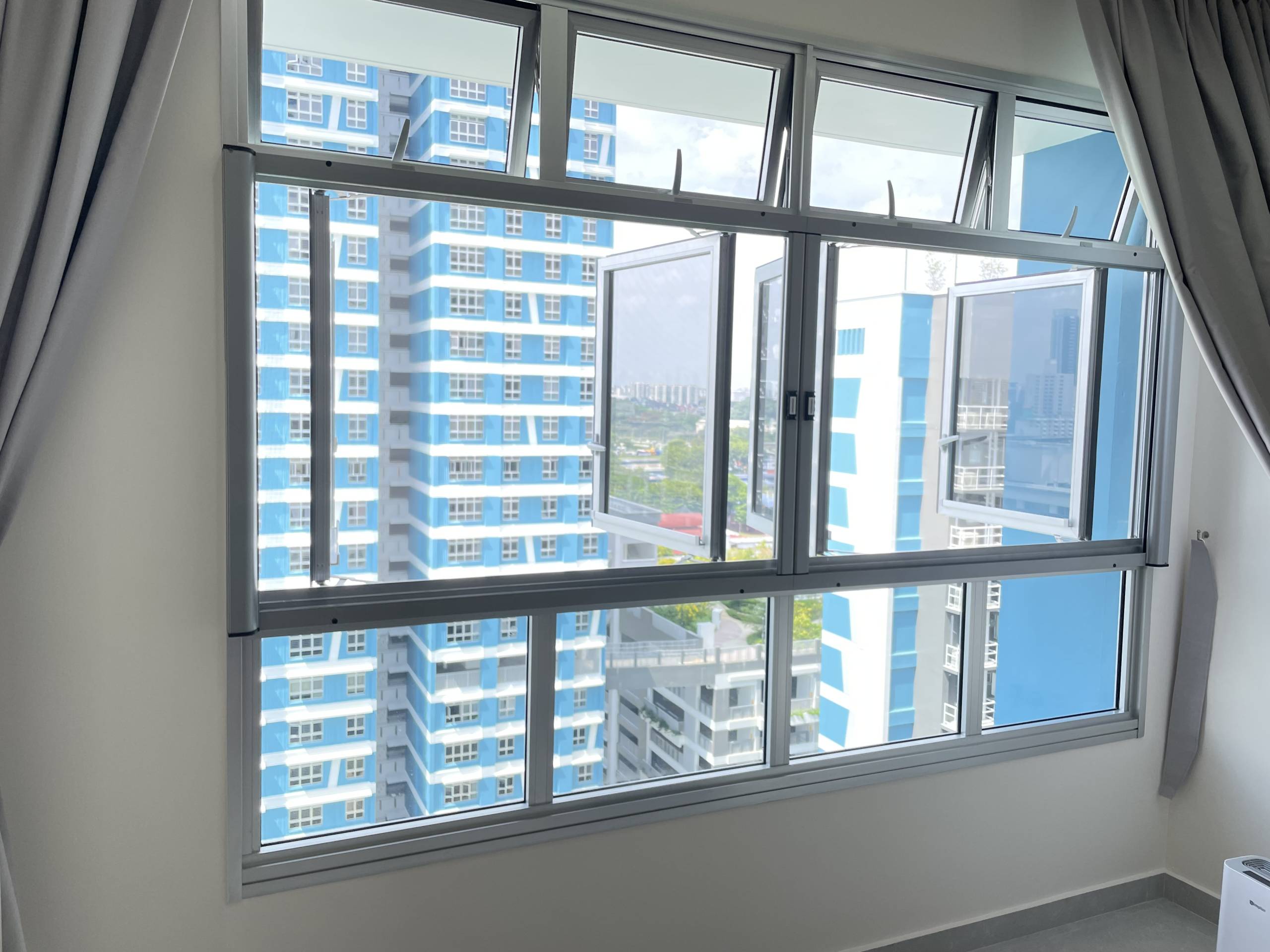 Wide Dinomesh insect screen installation on a high-rise bedroom window with city view.