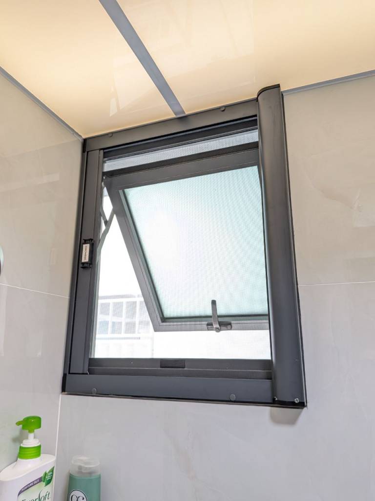 Angled view of the Dinomesh retractable mesh on an open bathroom window.