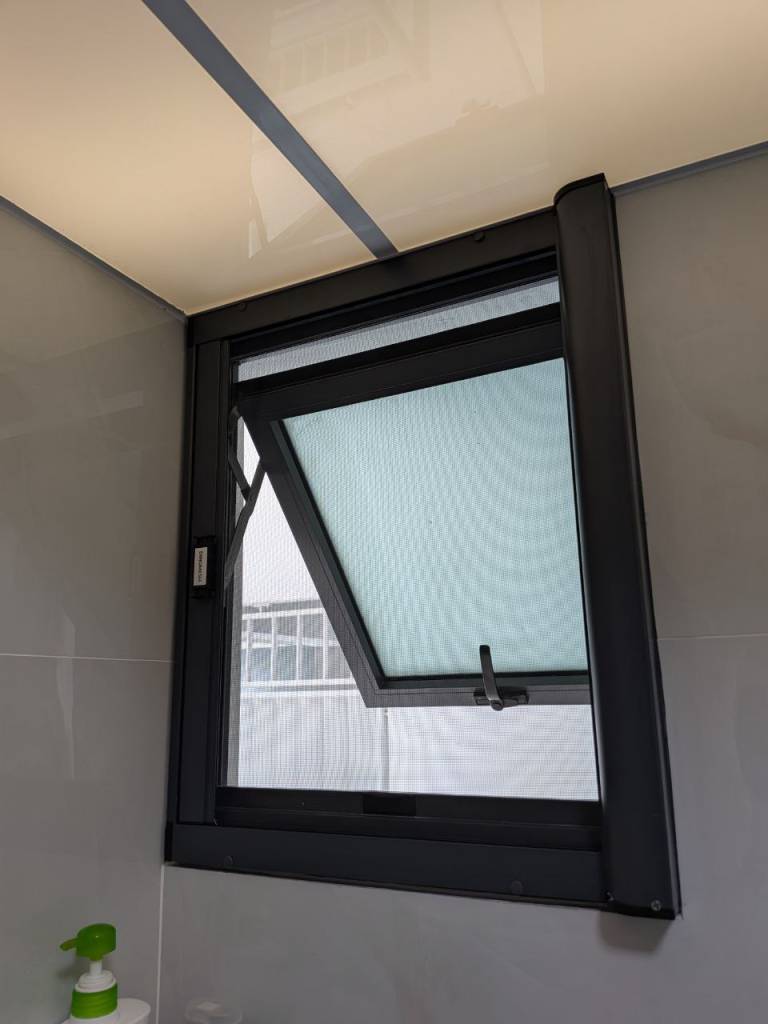 Dinomesh retractable insect screen installed on a black-framed top-hung bathroom window.